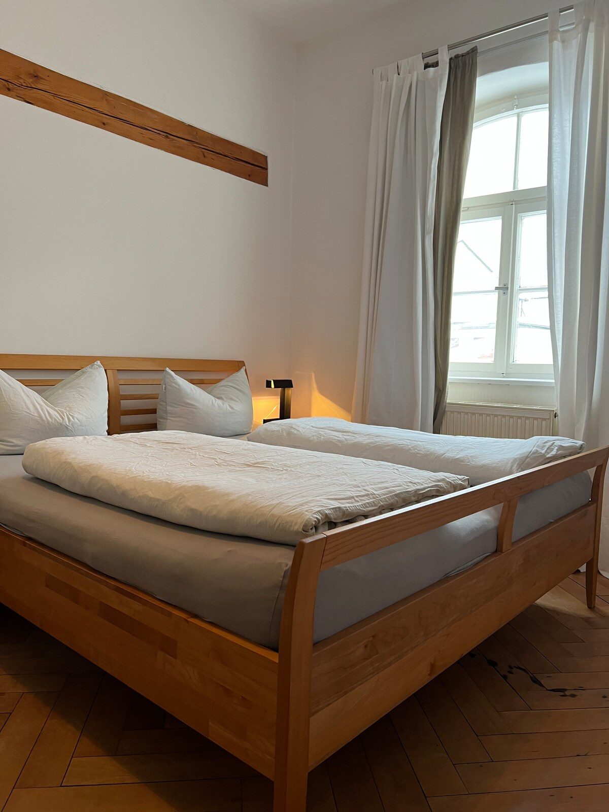 Schlafzimmer mit metallfreiem Massivholzbett von TEAM7 vor hellen Wänden.