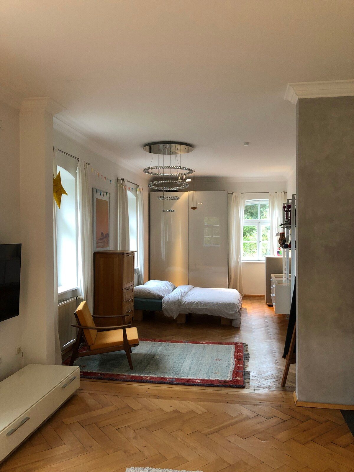 Großes, lichtdurchflutetes Schlafzimmer der Wohnung mit Fischgrätparkett.