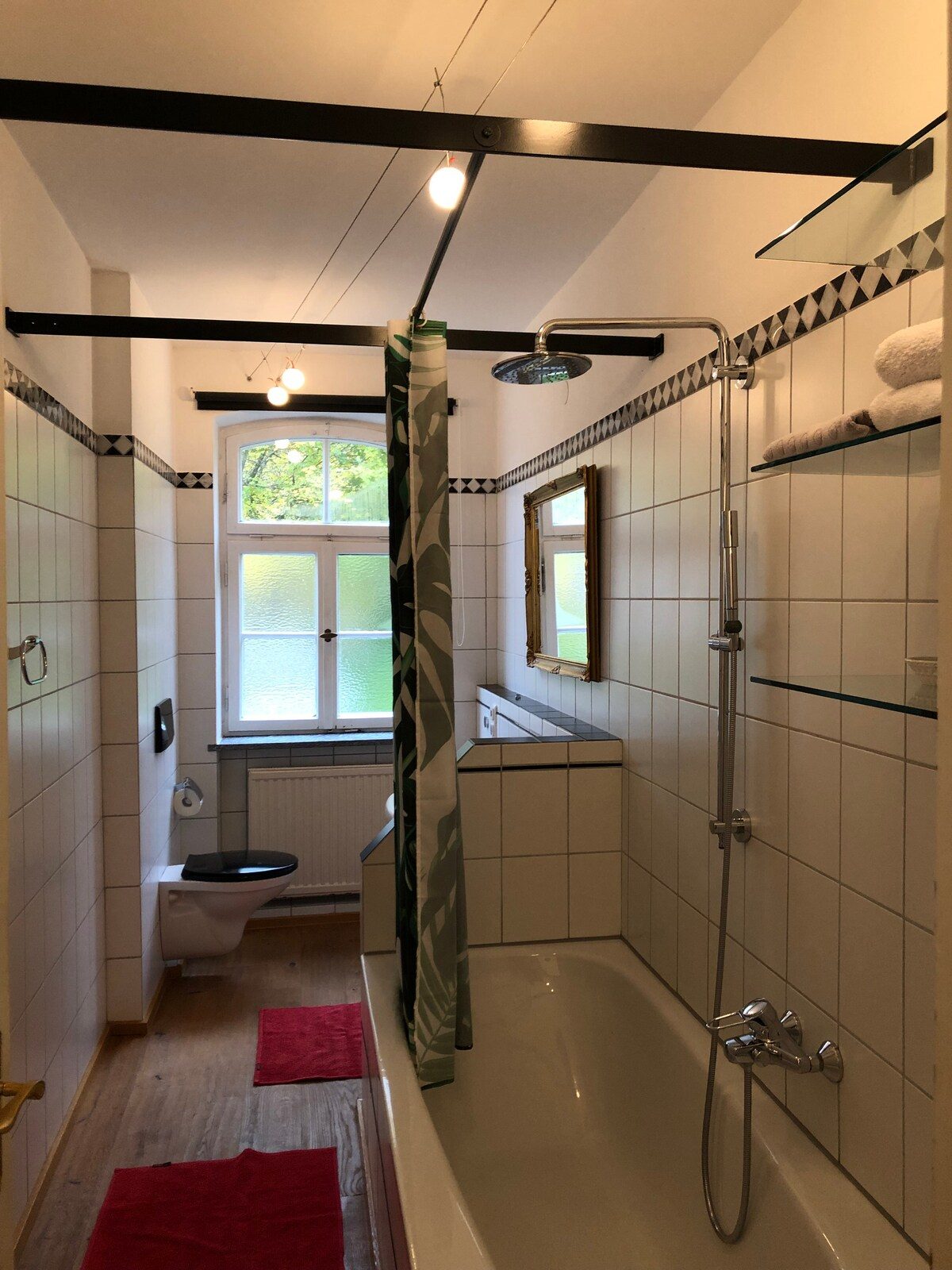 Bad der Wohnung mit freistehender Badewanne und sichtbaren Holzbalken.