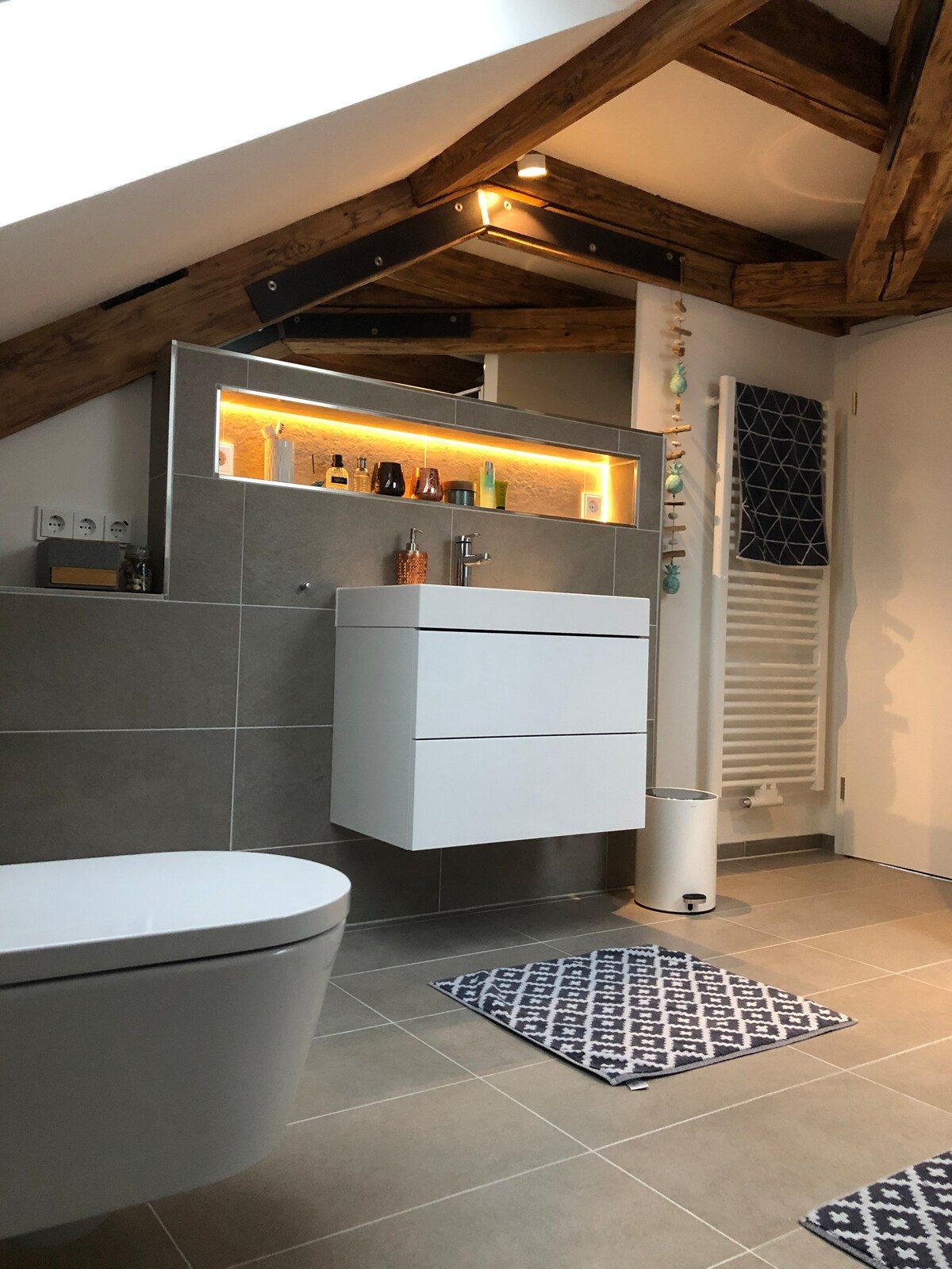 Helles Loft-Bad mit Badewanne unter dem Dachfenster.